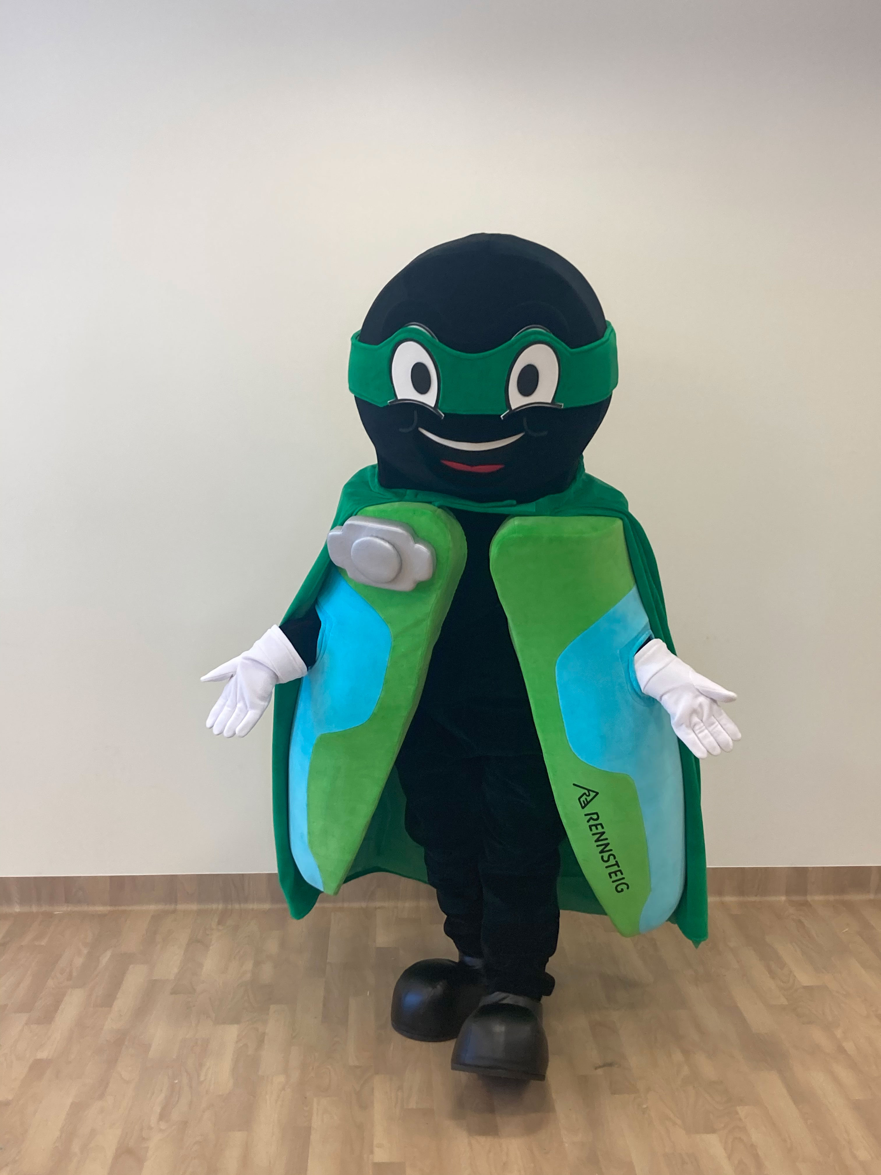 Na fotografii widnieje maskotka w postaci stroju reklamowego imitującego zaciskarkę do kabli, pozująca do zdjęcia w siedzibie firmy Elabika